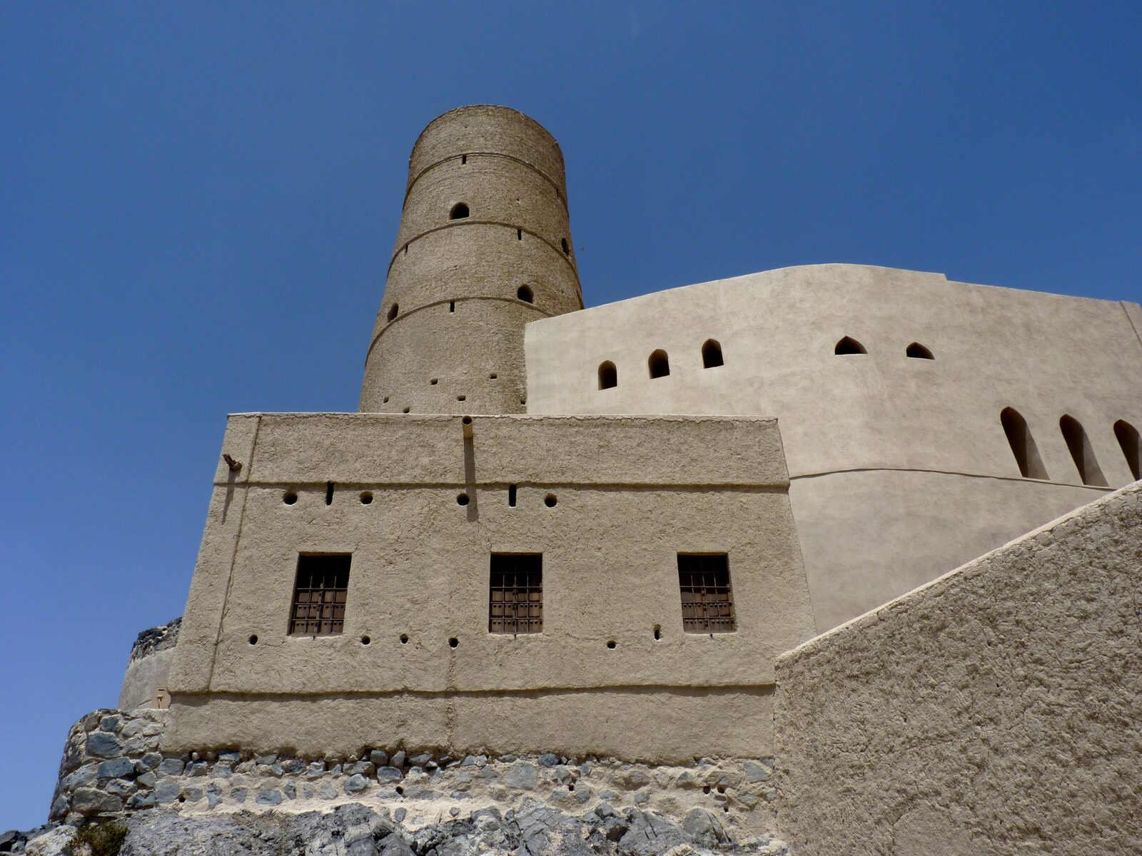 Bahla Fort's weathered adobe walls and towers on their stone foundations, Oman