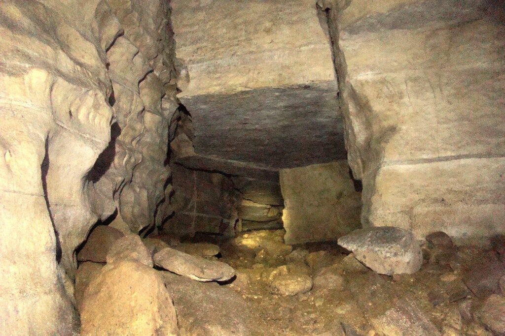 A long, narrow corridor inside the Cueva de los Tayos, its rock walls rising straight and flat on either side.