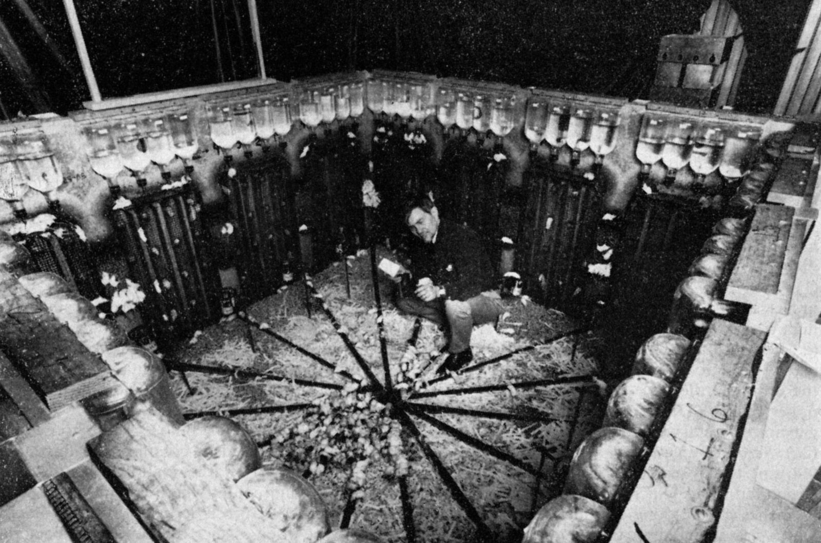 John B. Calhoun standing inside his circular metal mouse-universe enclosure, reaching in among the mice