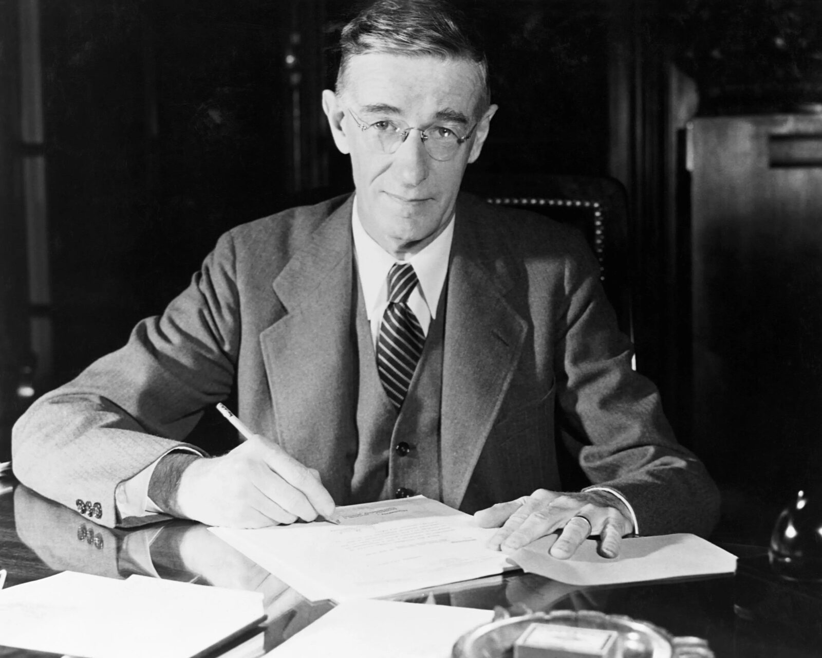 Black-and-white formal portrait of Dr. Vannevar Bush seated at a desk, early 1940s